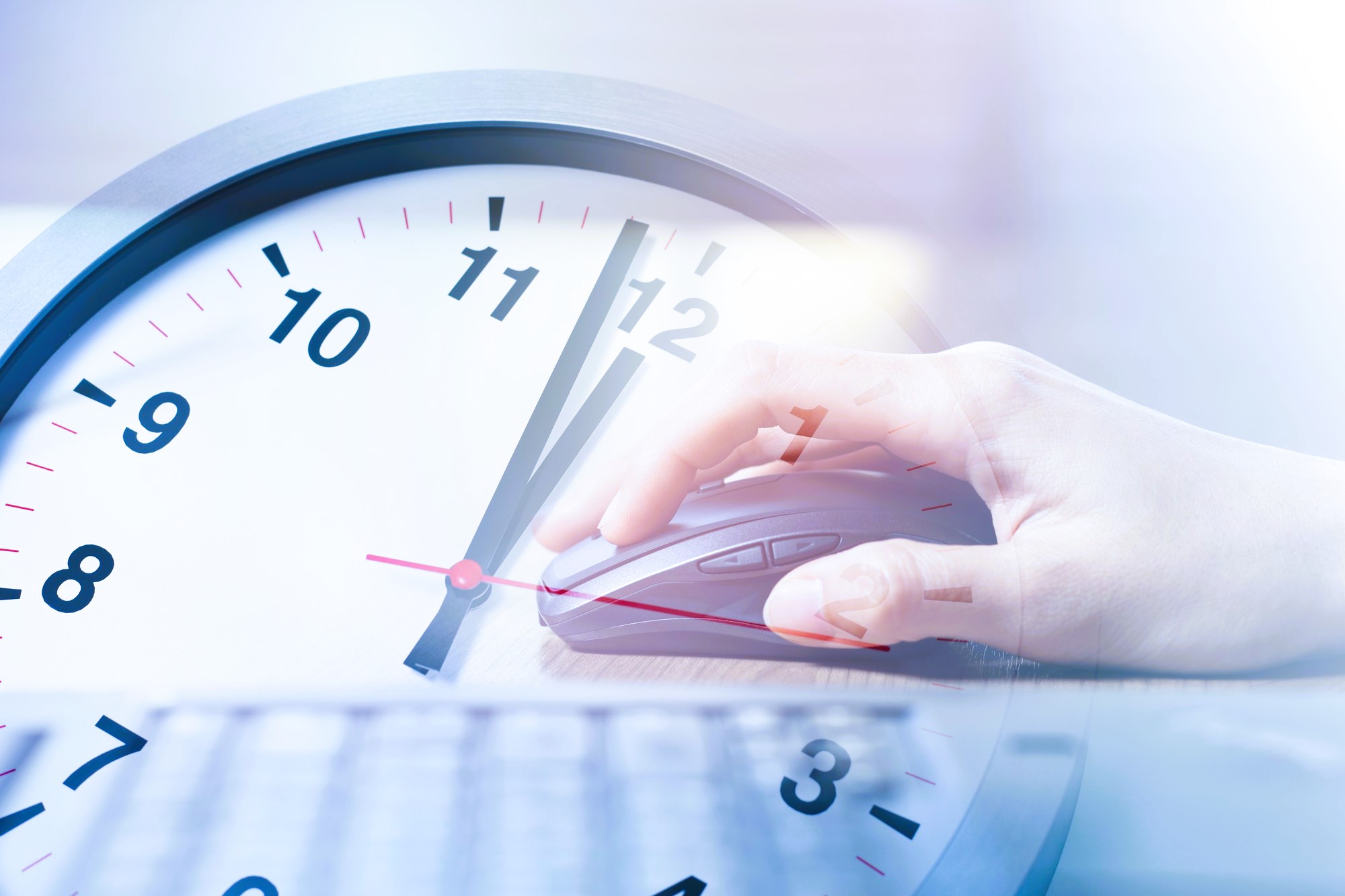 Hand using a mouse with a large wall clock in the background, representing time tracking in modern digital work.