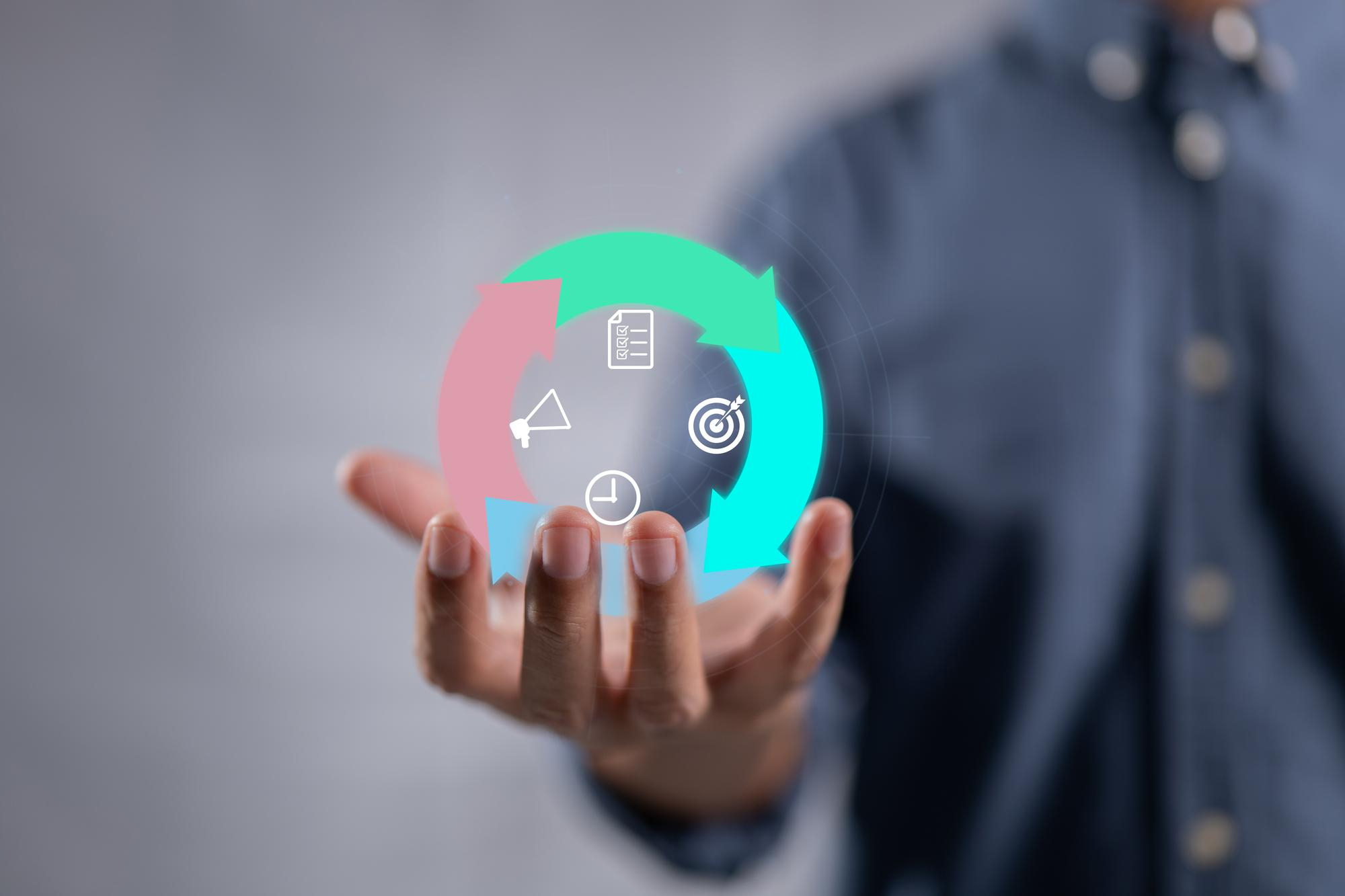 A person holding a holographic diagram of a project management lifecycle, with icons for planning, goals, and time.