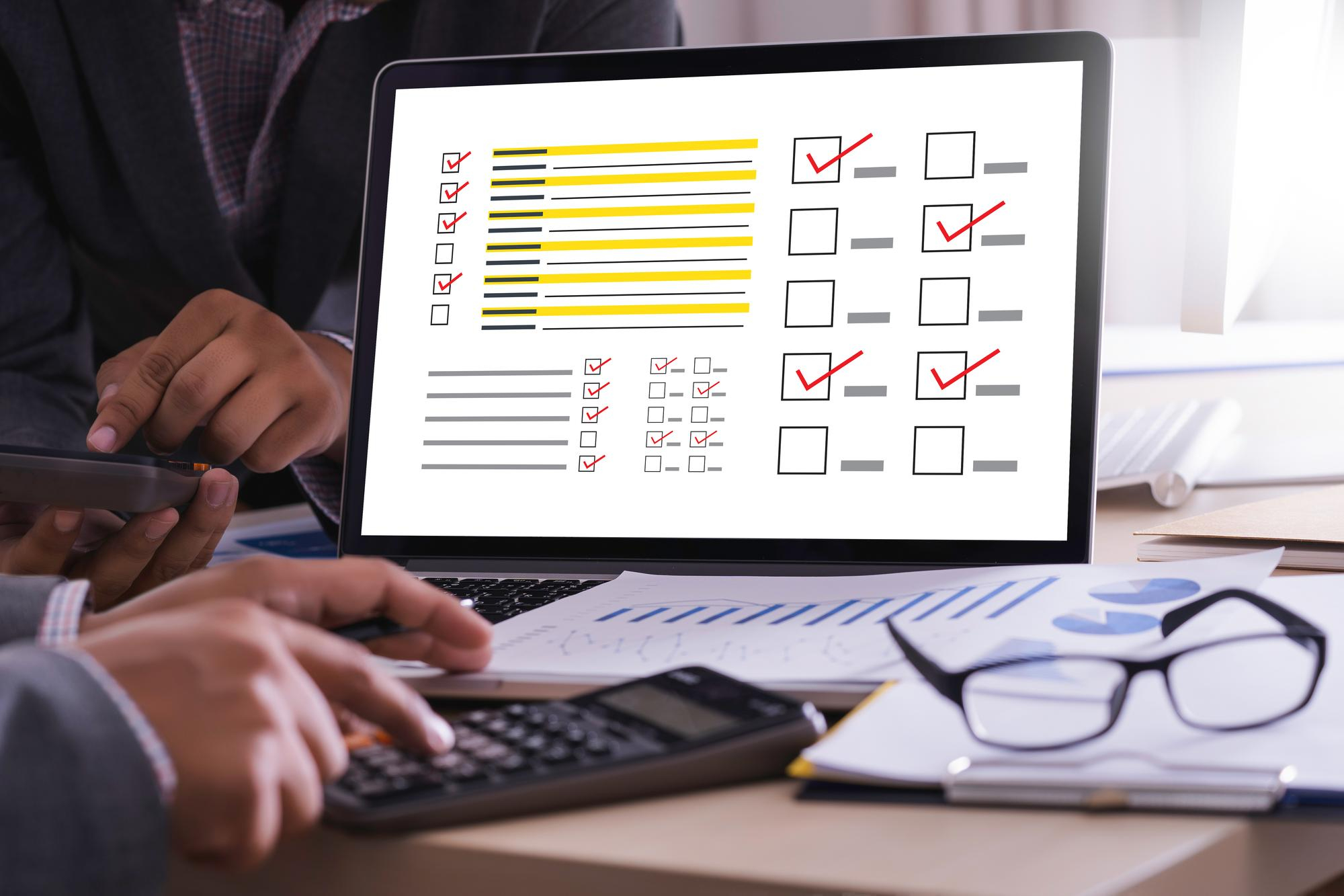 Engineers reviewing a digital checklist on a laptop to debug and stabilize a CI/CD pipeline.