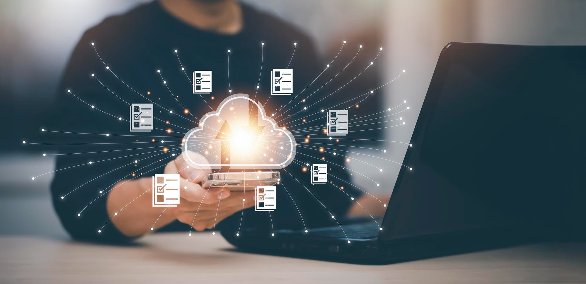 Person holding a smartphone in front of a laptop with a glowing cloud icon and digital checklists radiating outward, symbolizing a cloud project questionnaire.